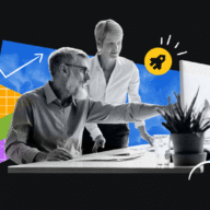 two coworkers looking at a computer screen, one of them pointing at something on the screen while the other looks on